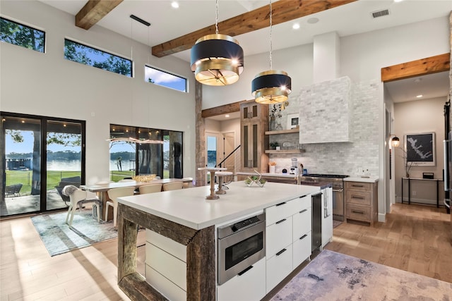 13555 Broken Arrow, Malakoff, TX 75148 - kitchen with a towering ceiling, modern cabinets, stainless steel microwave, light wood-style flooring, and white cabinetry