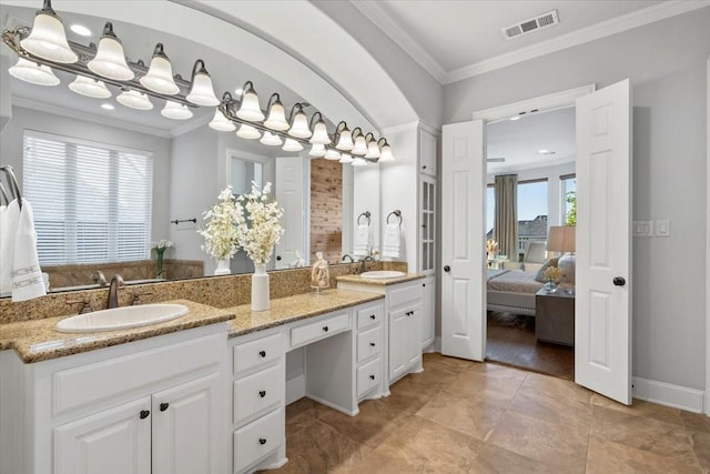 ensuite bathroom featuring crown molding, double vanity, and baseboards