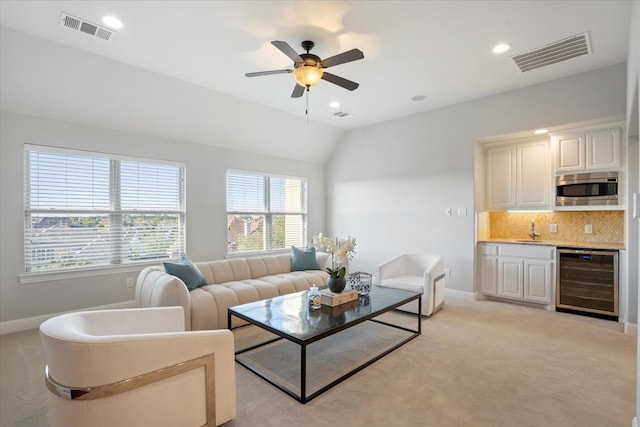 living room with beverage cooler, a ceiling fan, baseboards, light carpet, and lofted ceiling