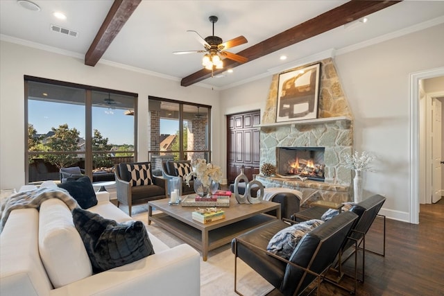 living room featuring ceiling fan, beamed ceiling, wood finished floors, a stone fireplace, and baseboards