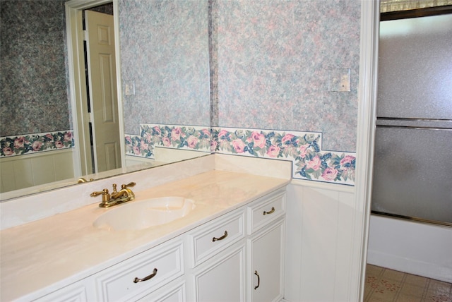 bathroom featuring wallpapered walls, a decorative wall, vanity, and a wainscoted wall