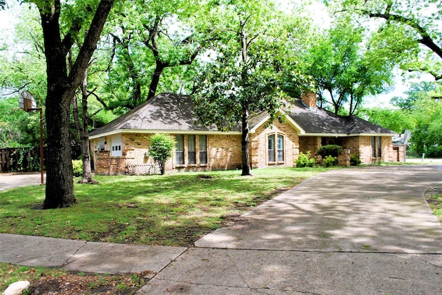 ranch-style house featuring brick siding, a chimney, a front yard, and concrete driveway