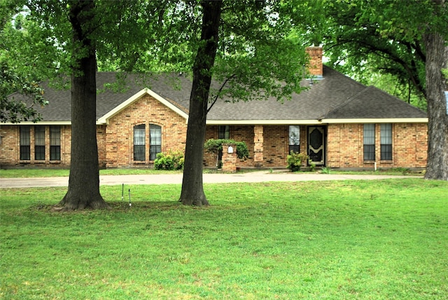 ranch-style house with brick siding, roof with shingles, and a front yard