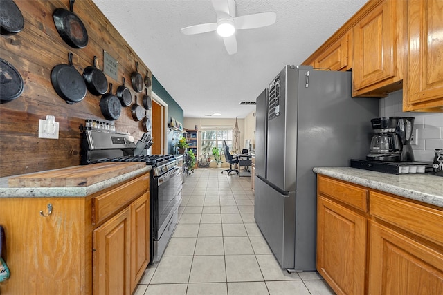 kitchen featuring stainless steel appliances, brown cabinetry, ceiling fan, and light tile patterned flooring