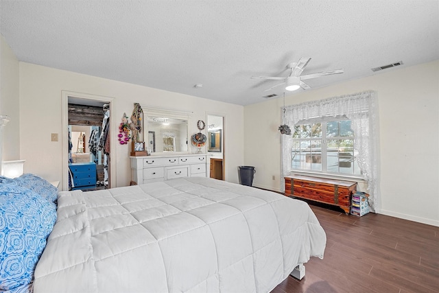 bedroom featuring dark wood finished floors, baseboards, visible vents, and a textured ceiling