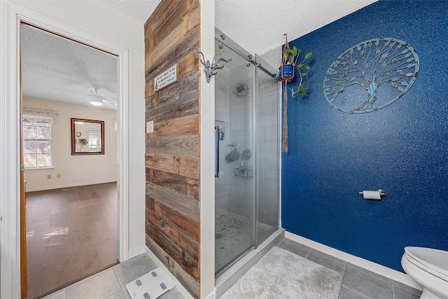 full bathroom featuring a shower stall, toilet, tile patterned floors, and a textured ceiling