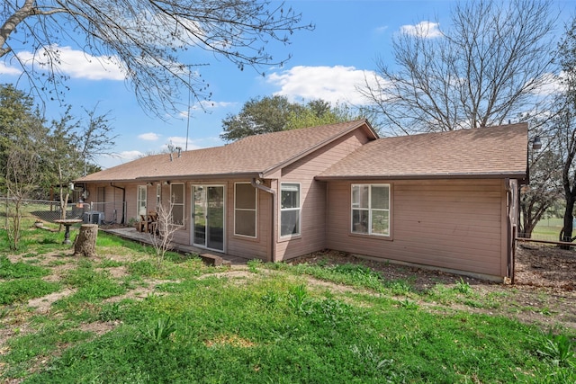 back of property with fence, a shingled roof, and cooling unit