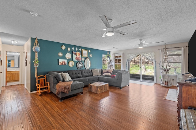 living room with a ceiling fan, wood finished floors, and a textured ceiling