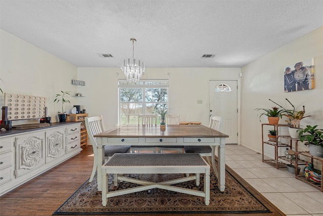 dining room with a chandelier, visible vents, and a textured ceiling