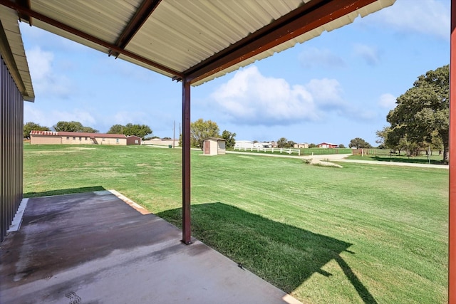 view of yard with fence, a patio, a shed, and an outbuilding