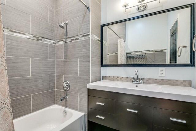 bathroom featuring shower / bath combo with shower curtain, vanity, and tasteful backsplash