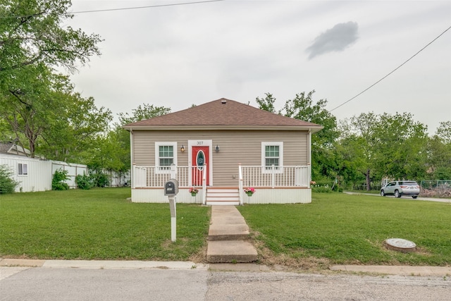 bungalow-style house featuring a front lawn, covered porch, and roof with shingles