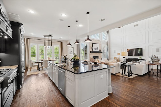 kitchen featuring dark wood-type flooring, plenty of natural light, stainless steel dishwasher, and a sink