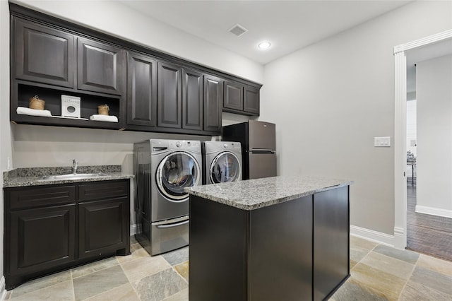 clothes washing area with a sink, visible vents, baseboards, independent washer and dryer, and cabinet space
