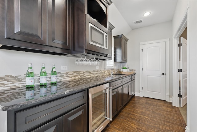 bar featuring wine cooler, a sink, stainless steel microwave, visible vents, and backsplash