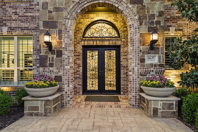 property entrance featuring french doors and brick siding