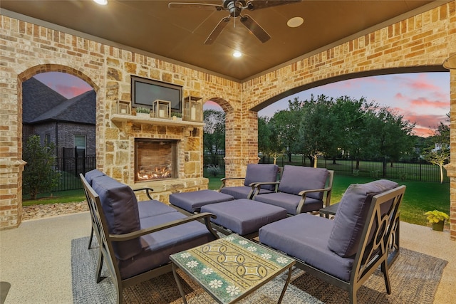 view of patio with fence, a ceiling fan, and an outdoor living space with a fireplace