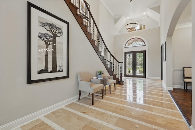 entrance foyer with baseboards, arched walkways, a notable chandelier, and stairway