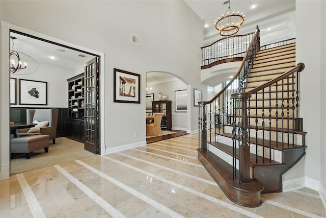 foyer featuring baseboards, arched walkways, a chandelier, and stairs