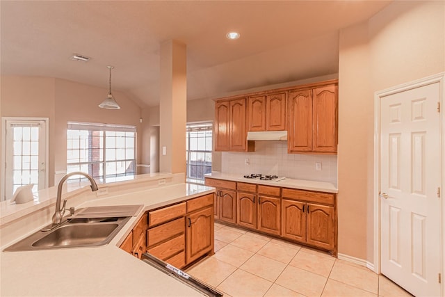 kitchen featuring lofted ceiling, under cabinet range hood, light countertops, a sink, and white stovetop