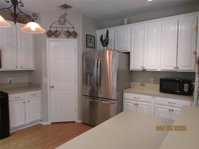 2709 Lakeside Dr, Burleson, TX 76028 - kitchen featuring light wood-type flooring, visible vents, black microwave, light countertops, and stainless steel refrigerator with ice dispenser