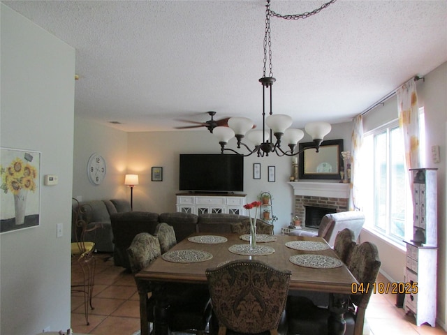 2709 Lakeside Dr, Burleson, TX 76028 - dining room with tile patterned flooring, a brick fireplace, a textured ceiling, and a notable chandelier