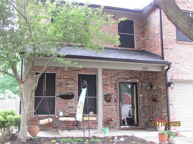 2709 Lakeside Dr, Burleson, TX 76028 - view of exterior entry featuring brick siding, a porch, roof with shingles, and a garage