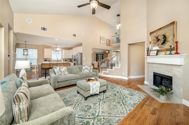 7612 Trevino Dr, Plano, TX 75025 - living area featuring a ceiling fan, light wood finished floors, stairs, baseboards, and a tiled fireplace