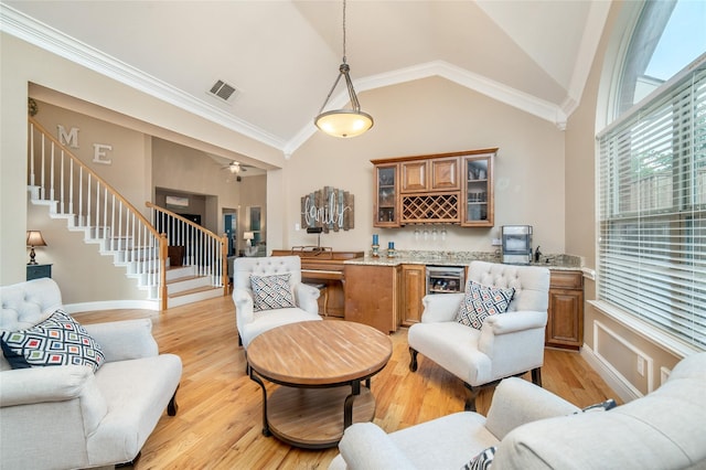 7612 Trevino Dr, Plano, TX 75025 - living area with stairs, bar with sink, high vaulted ceiling, light wood-type flooring, and ornamental molding