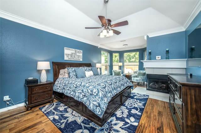 7612 Trevino Dr, Plano, TX 75025 - bedroom featuring crown molding, wood finished floors, baseboards, a tiled fireplace, and a ceiling fan