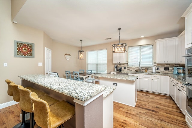 7612 Trevino Dr, Plano, TX 75025 - kitchen featuring a kitchen island, tasteful backsplash, light wood finished floors, white cabinets, and recessed lighting