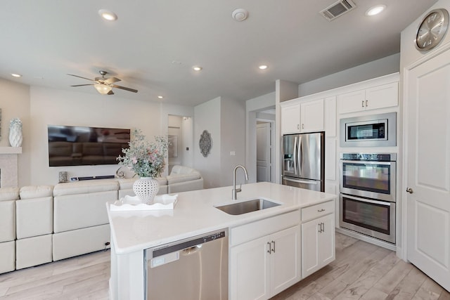kitchen with a sink, open floor plan, a center island with sink, appliances with stainless steel finishes, and visible vents