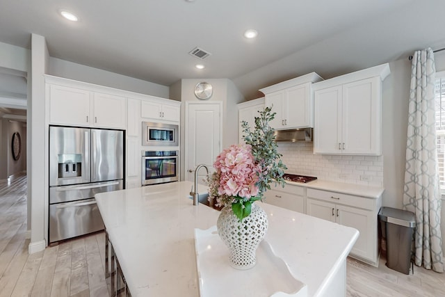kitchen with backsplash, appliances with stainless steel finishes, visible vents, and white cabinets
