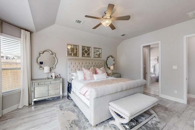 bedroom with lofted ceiling, visible vents, light wood finished floors, and connected bathroom