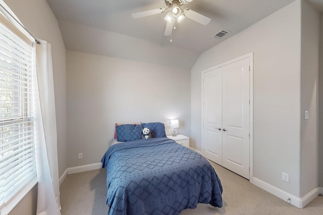 bedroom with lofted ceiling, a closet, baseboards, light colored carpet, and ceiling fan