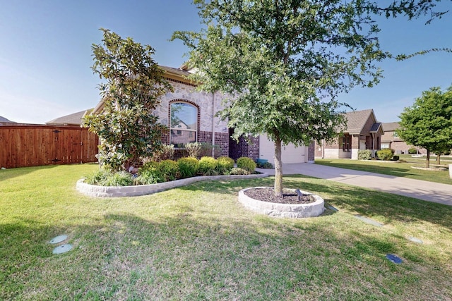 view of property hidden behind natural elements featuring concrete driveway, brick siding, fence, and a front yard