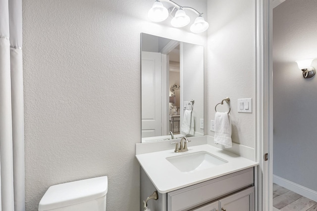 bathroom with wood finished floors, vanity, and toilet