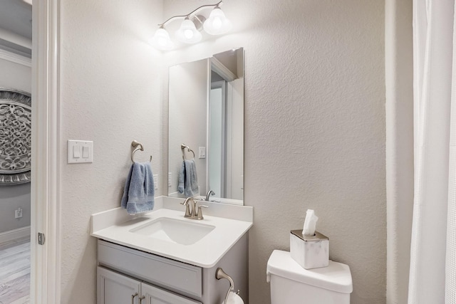 bathroom featuring wood finished floors, toilet, and vanity