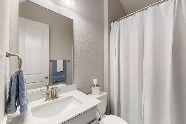 full bath with toilet, a textured wall, vanity, and curtained shower