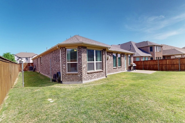 rear view of house featuring a fenced backyard, brick siding, a patio, and a lawn
