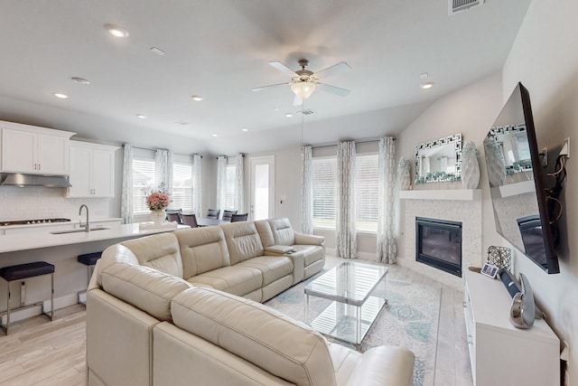 living room with light wood-style flooring, visible vents, recessed lighting, ceiling fan, and a stone fireplace