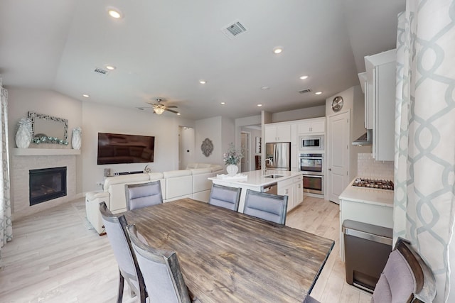dining space with visible vents, recessed lighting, light wood-style floors, a large fireplace, and ceiling fan