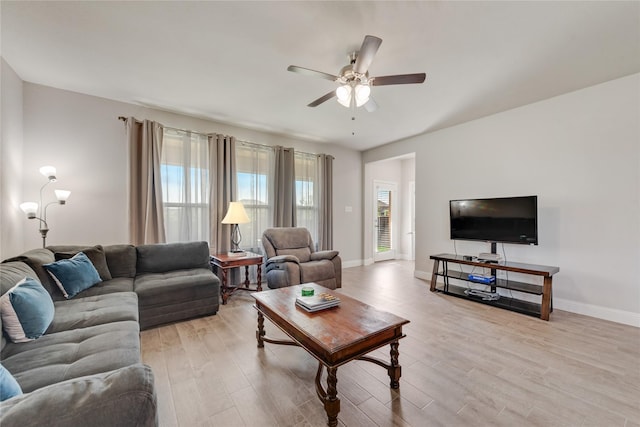 living room featuring baseboards, a ceiling fan, and light wood finished floors