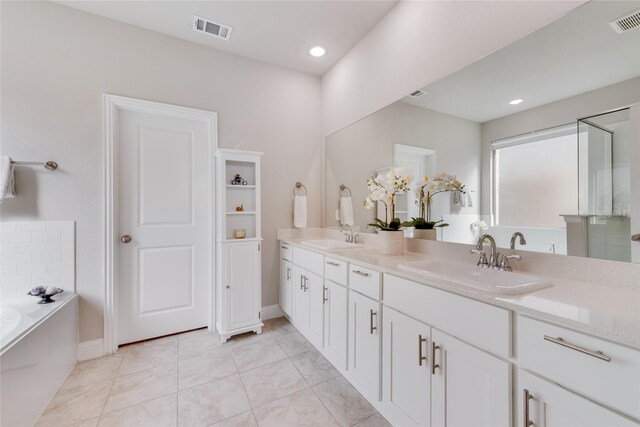 bathroom with a garden tub, a sink, and visible vents