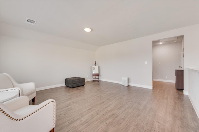 living area with wood finished floors, visible vents, and baseboards