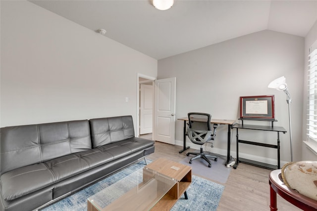 office area with baseboards, lofted ceiling, and light wood-type flooring