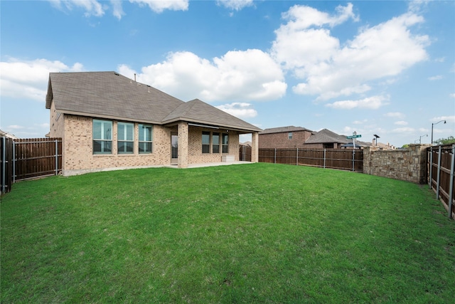 rear view of house featuring a fenced backyard, brick siding, and a lawn