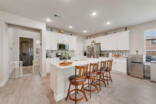kitchen with tasteful backsplash, visible vents, appliances with stainless steel finishes, and a sink