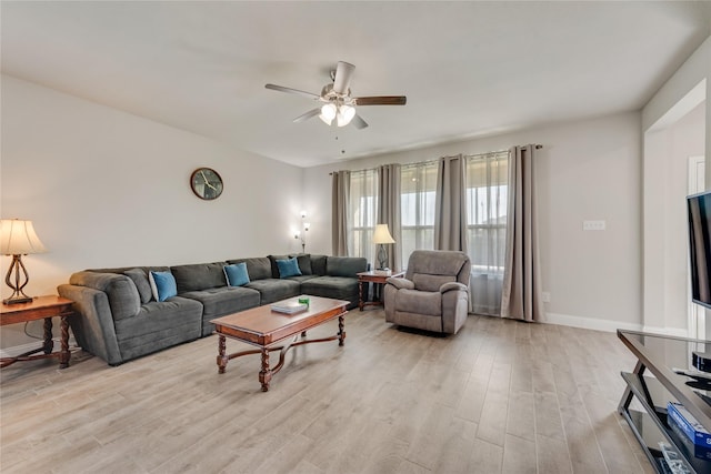 living area featuring light wood-style flooring, baseboards, and a ceiling fan