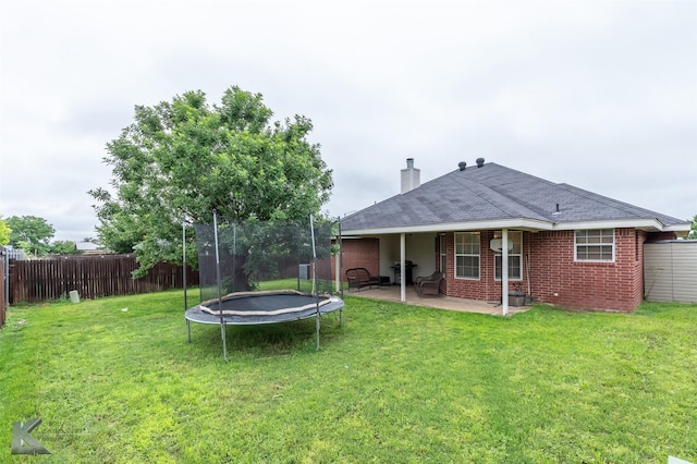 4910 Coyote Run, Abilene, TX 79602 - back of property featuring a trampoline, a patio, brick siding, and a chimney